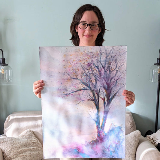 Person holding a painting of a tree with pastel colors in a room.