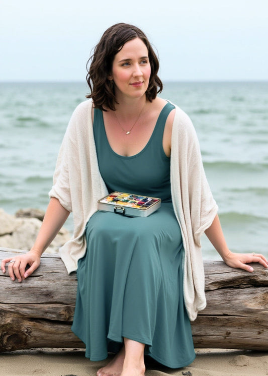Tara Shoemaker sitting on the beach with watercolor paints. Image generated with the help of AI tools.
