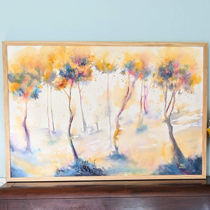 Framed abstract painting of trees with colorful brushstrokes on a light blue wall.