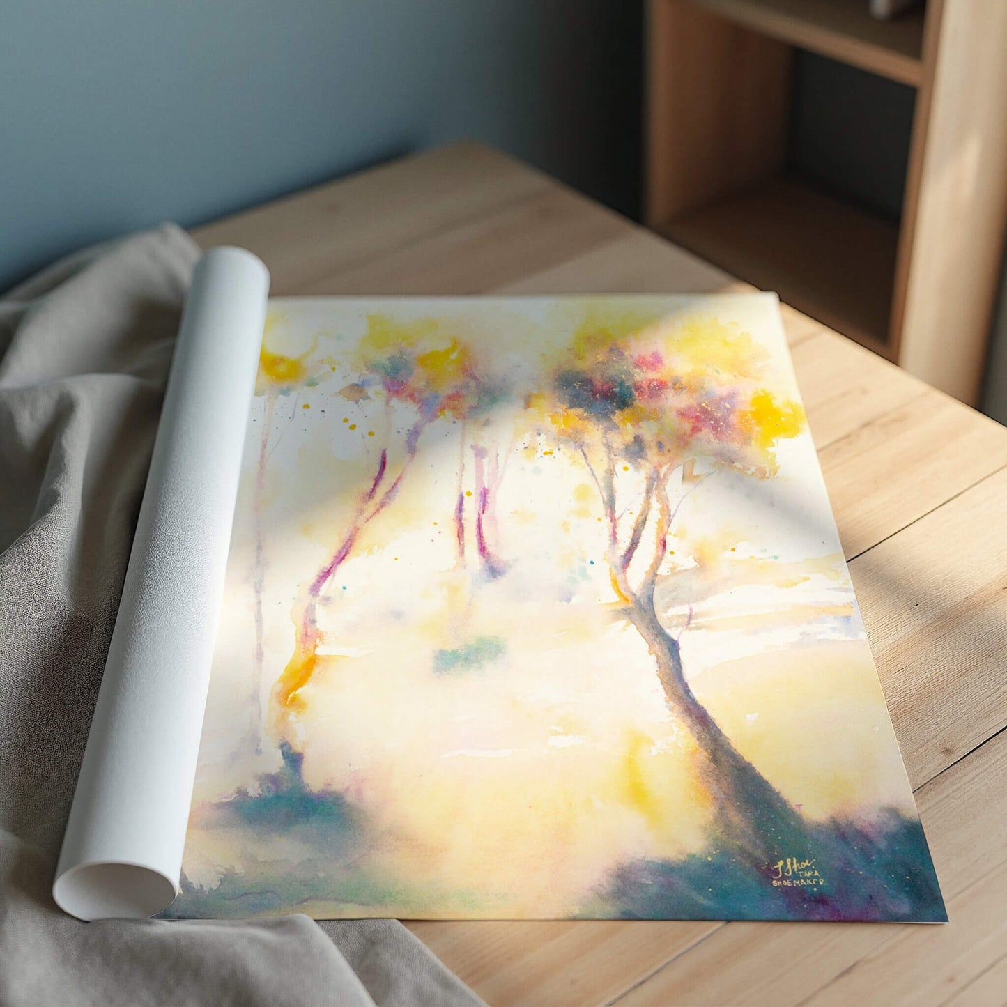 Colorful rolled up abstract art print of trees on a wooden surface