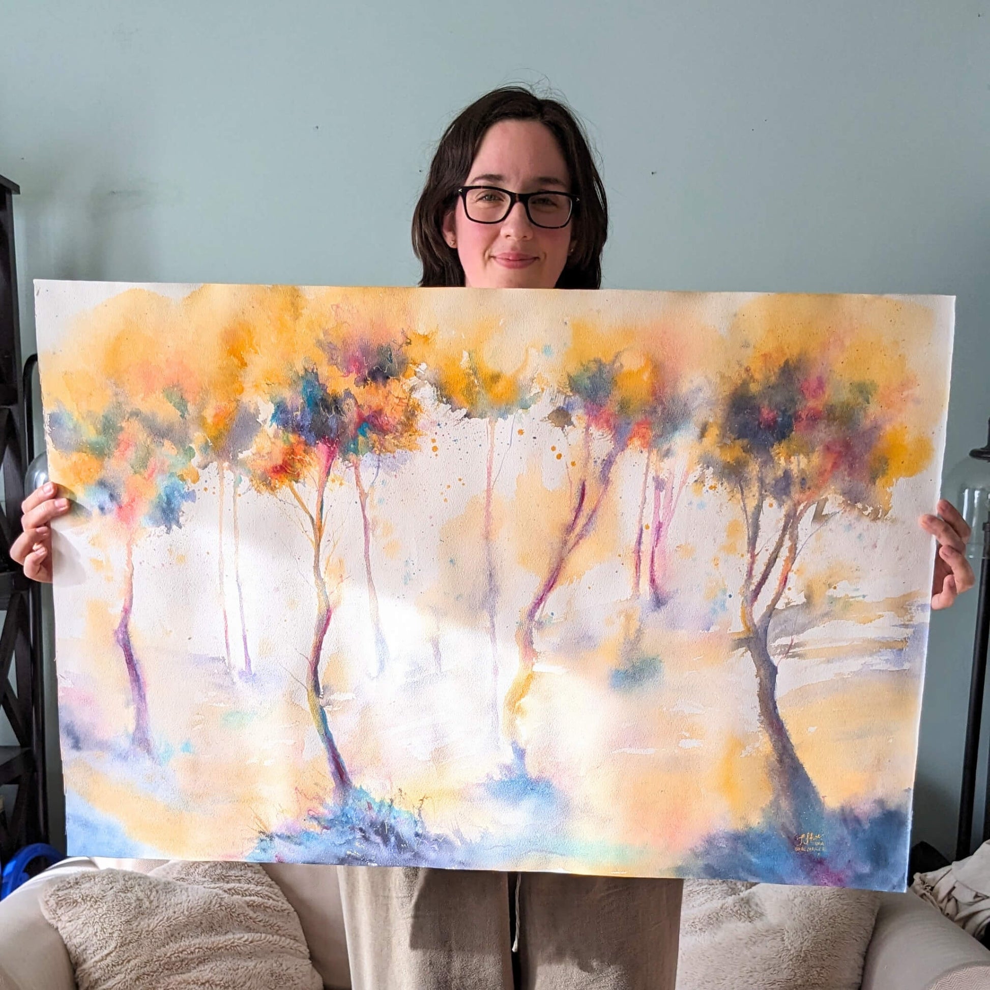 Person holding a colorful abstract painting of trees