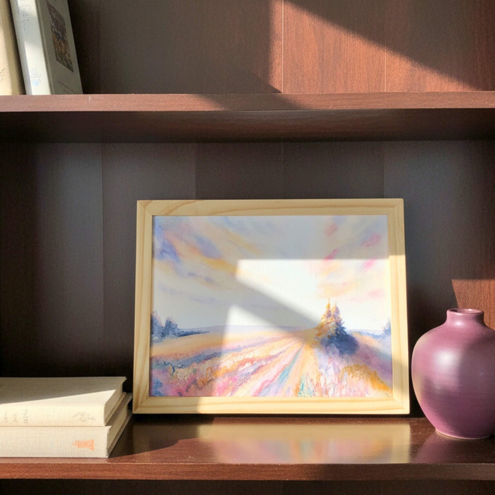 Framed abstract painting on a wooden shelf with a pink vase and books.