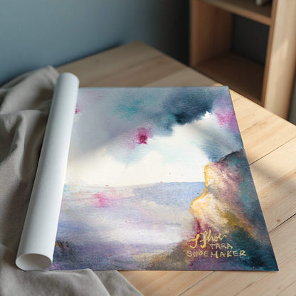 Rolled-up art print with a colorful landscape and signature on a wooden surface.