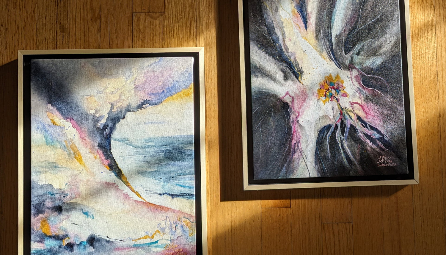 Two framed abstract artworks on a wooden surface