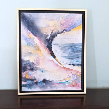 Framed abstract painting with colorful brushstrokes on a light blue wall.