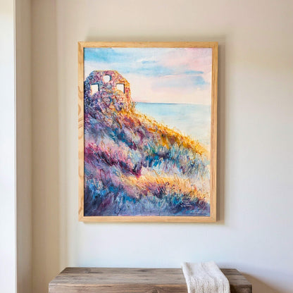 Framed painting of a colorful ruin above wild grasses on a wall above a wooden bench