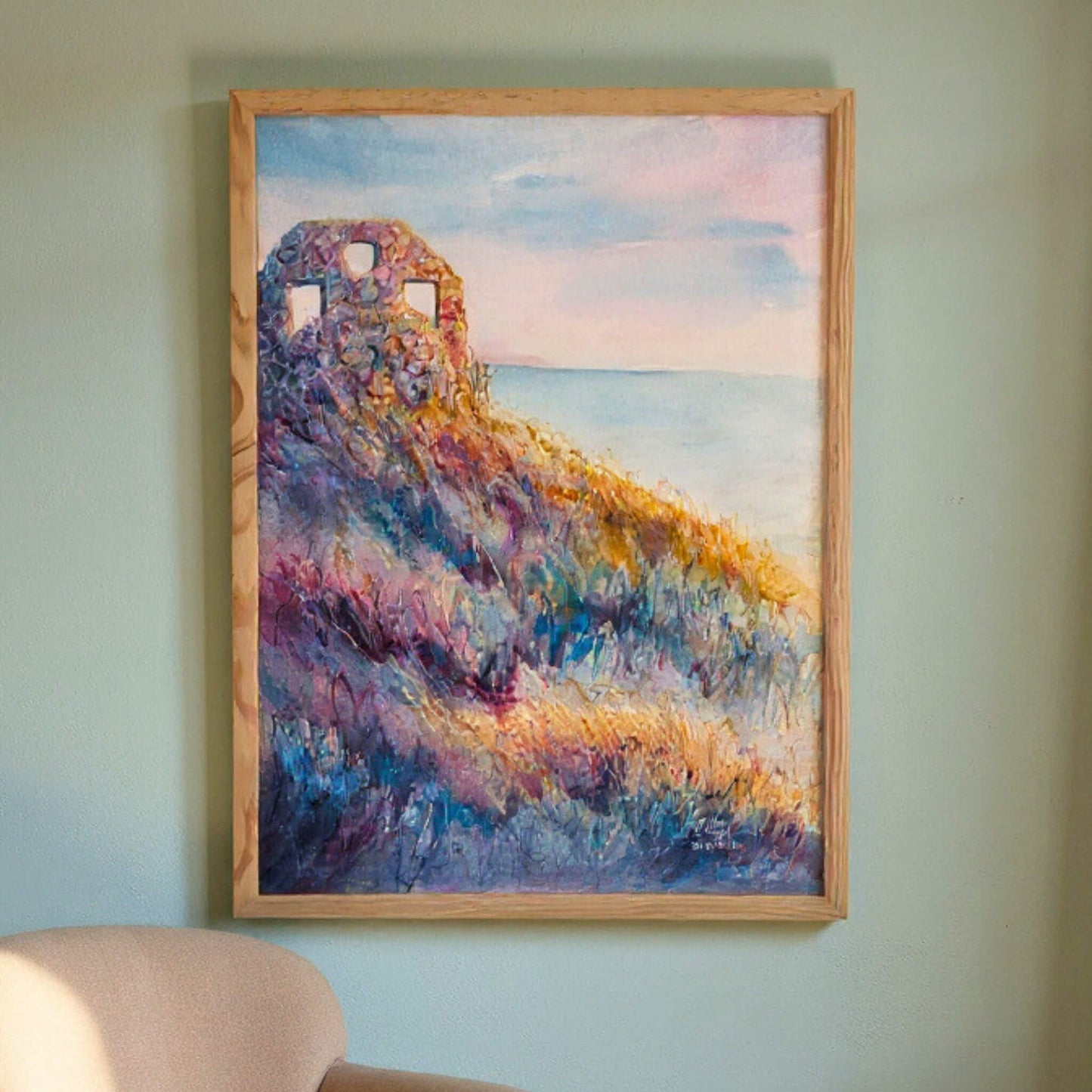 Framed painting of a colorful landscape with a castle on a wall.