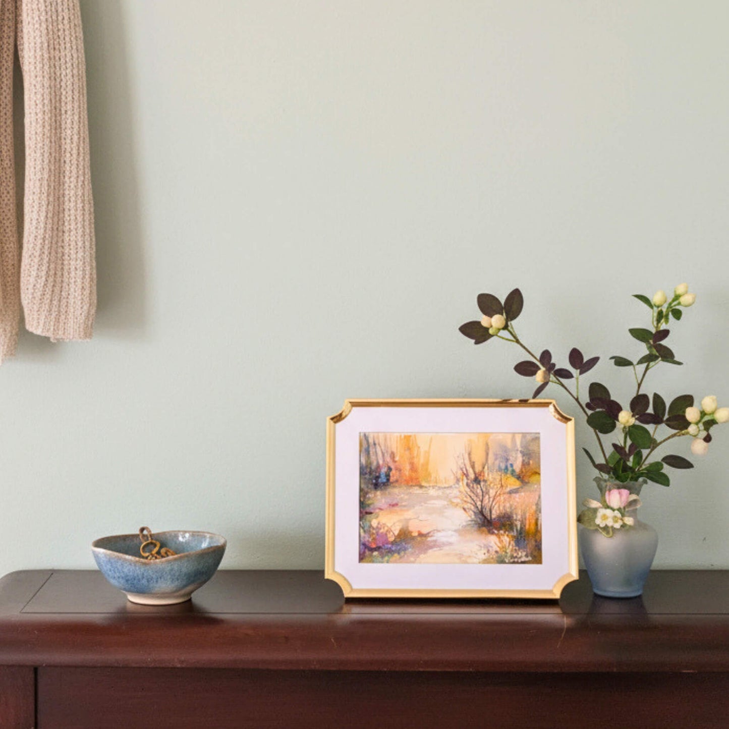Framed artwork on a wooden surface with a light green wall in the background
