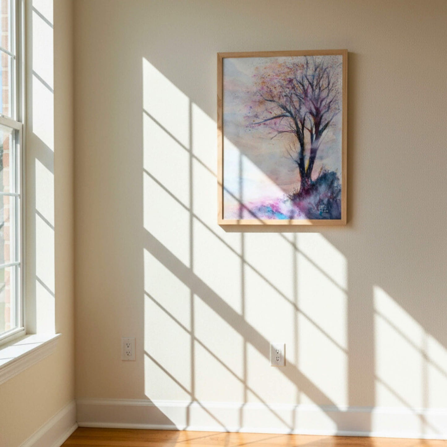 Framed artwork of a tree on a wall with sunlight casting shadows