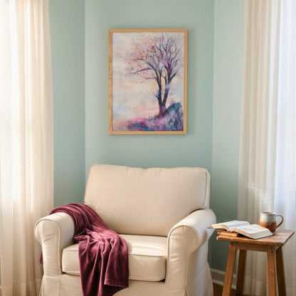 Beige armchair with a red blanket, wooden side table with a book and mug, and a framed tree painting on a light green wall.