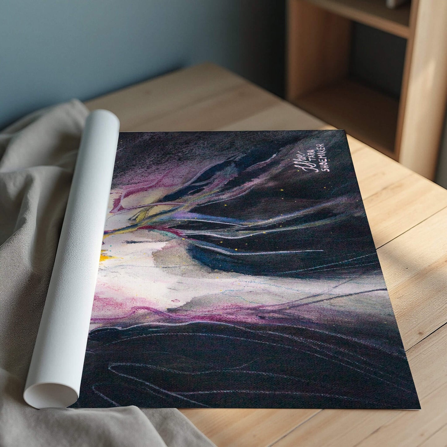 Rolled up abstract art print on a wooden surface.