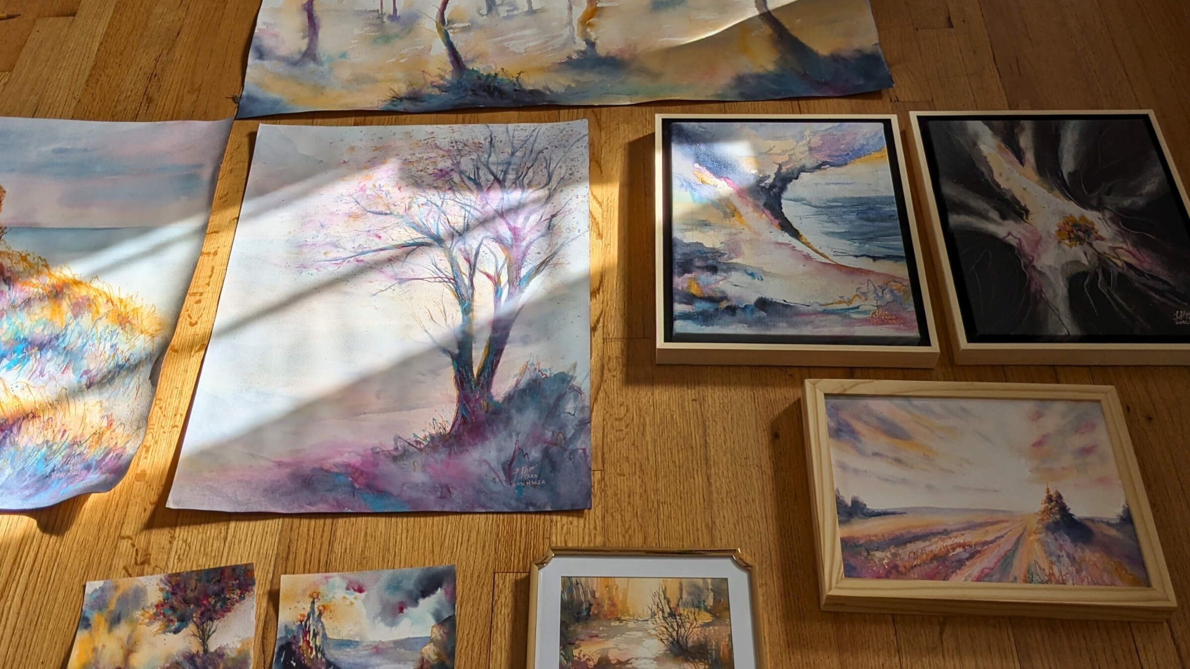 Collection of watercolor paintings on a wooden surface